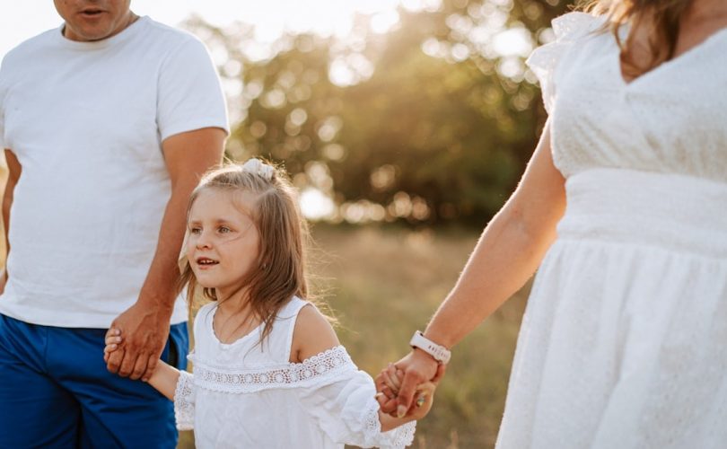 A man and a woman holding hands with a little girl