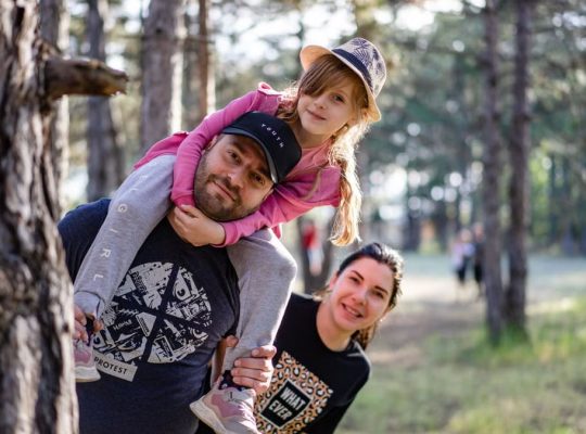 A joyful family enjoying a playful day in a sunlit forest park, capturing the essence of togetherness.